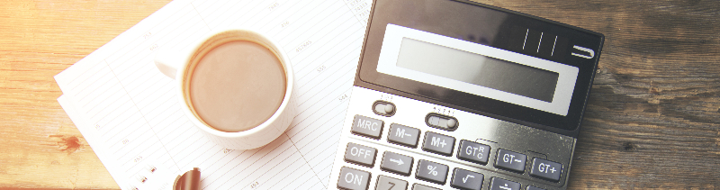 A pen, notepad, calculator, and a cup of coffee.